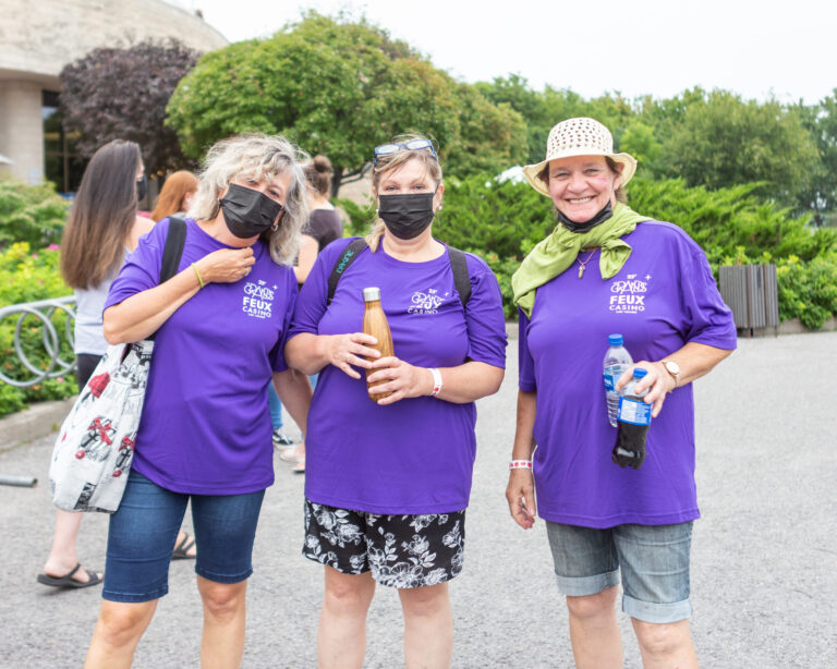Trois bénévoles qui portent des chandails mauves des Grands Feux et des masques noirs.